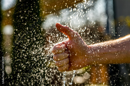 Closeup photo of man washing hands with big splash into hands