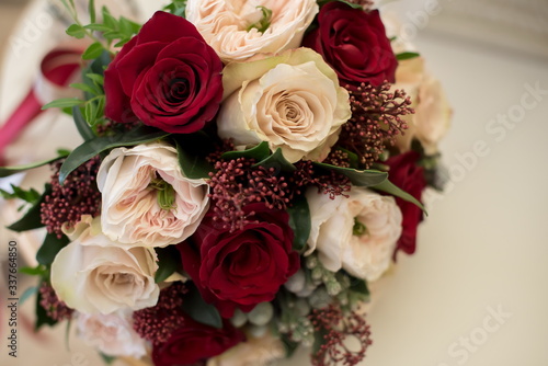 Bridal bouquet of red and cream roses, eustoma and ornamental plants  © Maria