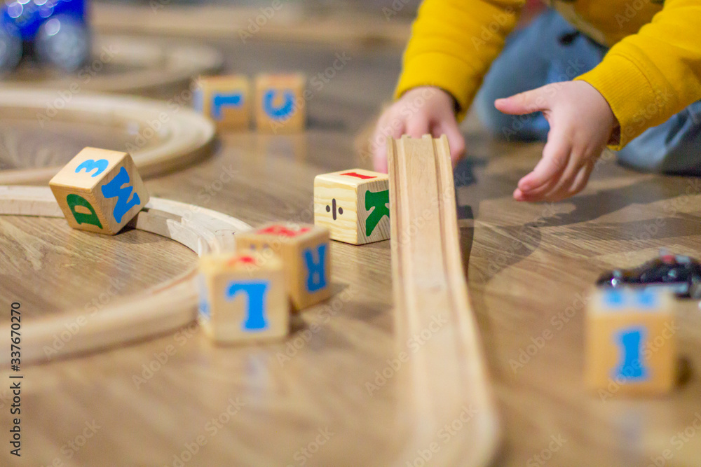 Child playing with blocks and a wooden train track