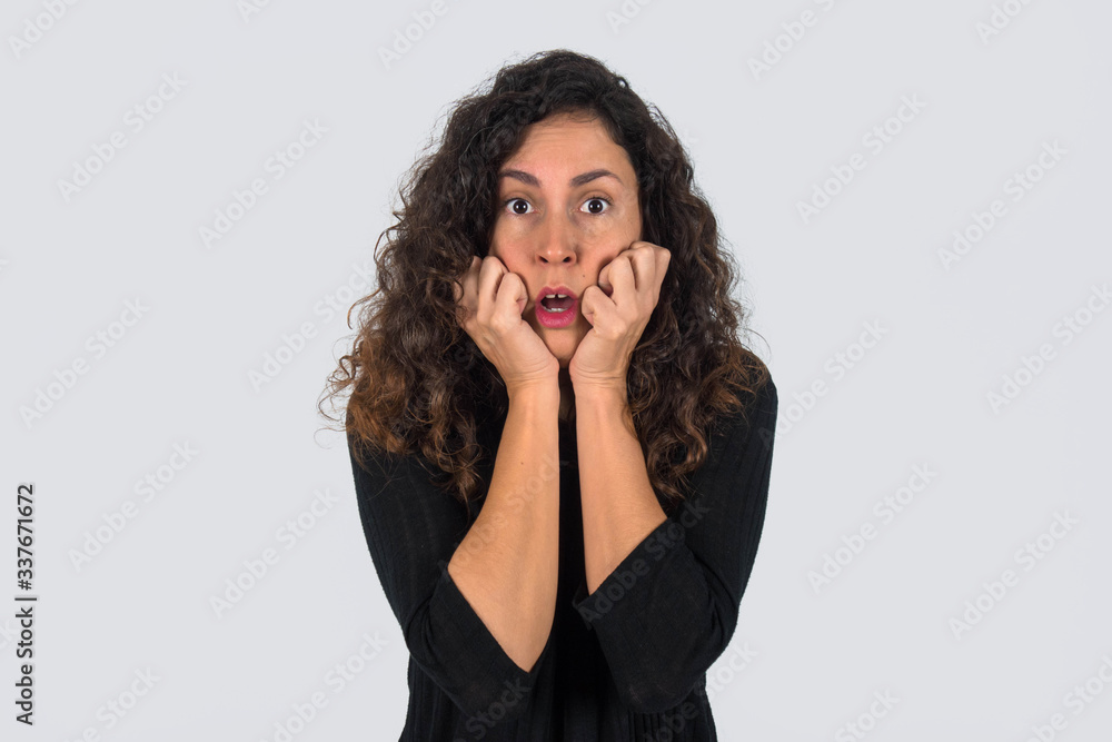 Brunette woman with curly hair dressed in black. Pretty girl with expression of fear and terror. Brunette woman with curly hair dressed in black. Pretty girl with expression of fear and terror.