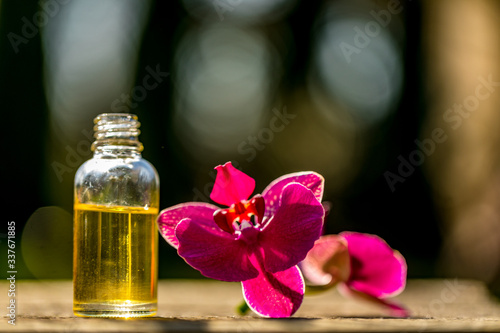 Spa still life with essential oils and orchid on bokeh background.