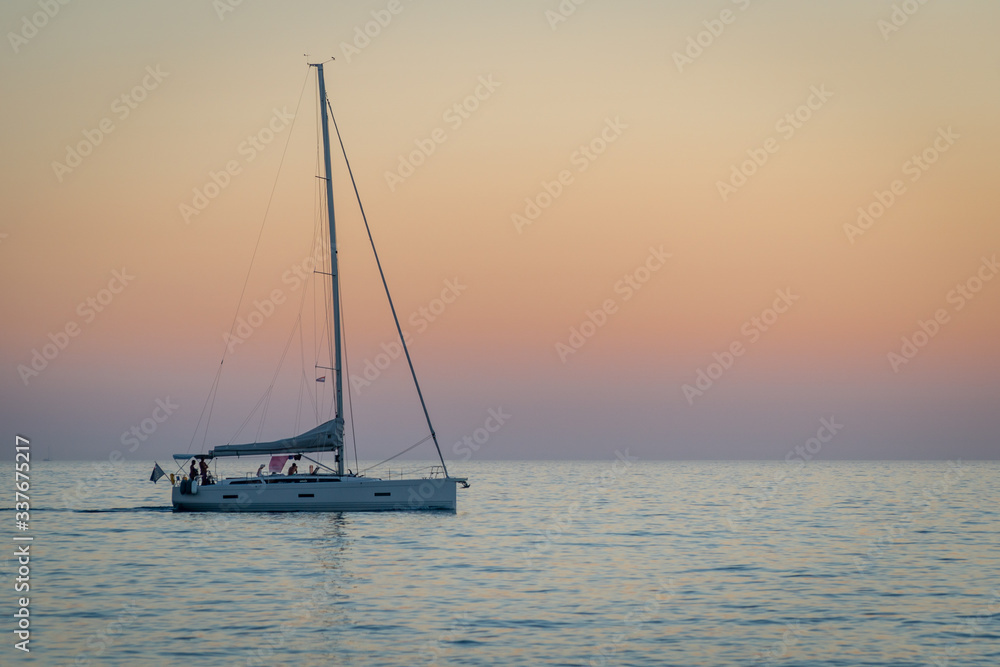 A yacht sailing alone on a calm sea at dusk.