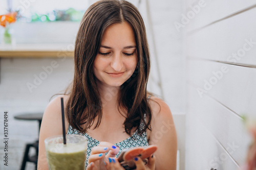 Girl in cafe with smoothie and phone. Pretty girl in dress with phone