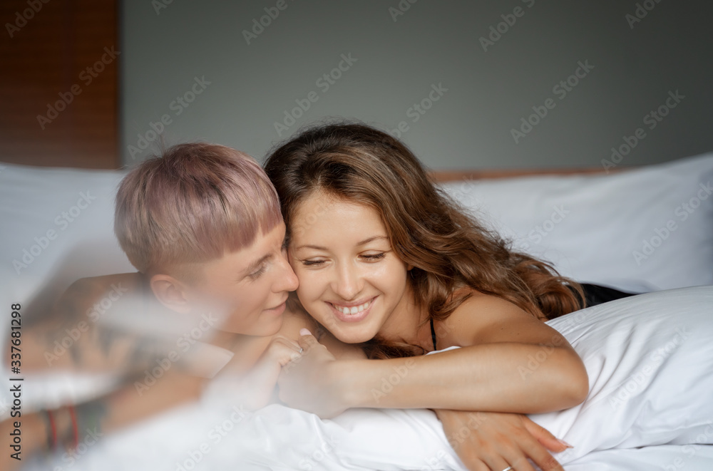 Two young sexy beautiful women girlfriends lesbian couple cuddling tenderly lie on the bed, attraction romance tenderness concept Two young sexy beautiful women girlfriends lesbian couple cuddling tenderly lie on the bed, attraction romance tenderness concept