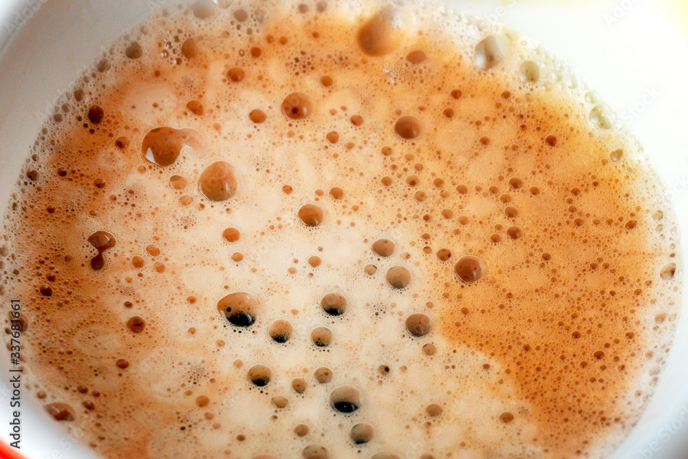macro shot showing the bubbles and texture of a delicious, hot cup of brown coffee with a light layer of foam. Image has copy space. selective close-up focus macro shot showing the bubbles and texture of a delicious, hot cup of brown coffee with a light layer of foam. Image has copy space. selective close-up focus