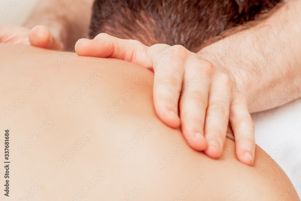Young man receiving back massage in spa beauty salon.