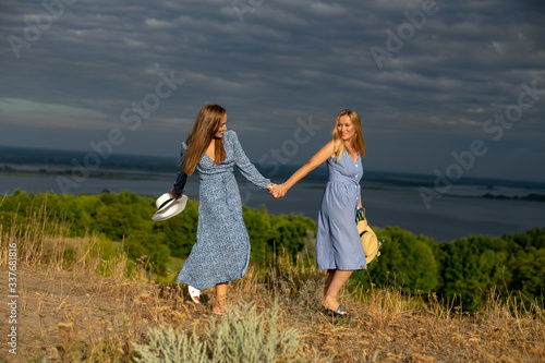 horizontal portrait of two cheerful young European women against the background of a river landscape