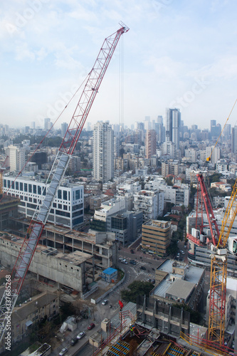 Modern city. Office building top view. Crane and building construction site against the blue sky. Isreal, Ramat Gan, Bnei Brak, Tel Aviv, Tel Aviv-Yafo