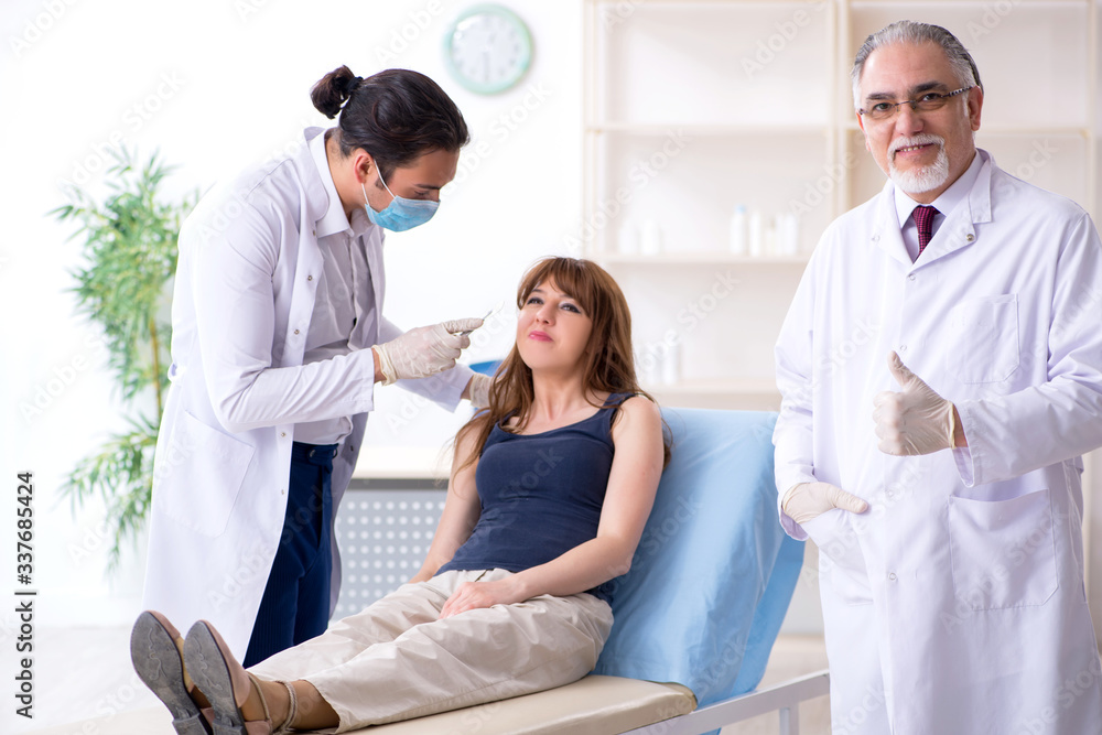 Obraz premium Two male doctors and young woman in plastic surgery concept