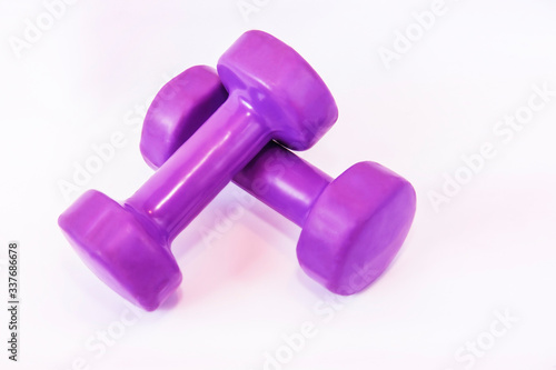 Pink lightweight dumbbells for gym or home for women and girls on light background for fitness