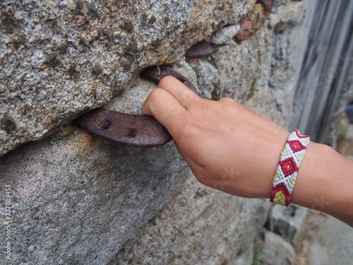 A horseshoe is inserted into the stone wall and a woman's hand grabs it, Camino de Santiago, Way of St. James, Journey from Dumbria to Muxia, Fisterra-Muxia way, Spain photo