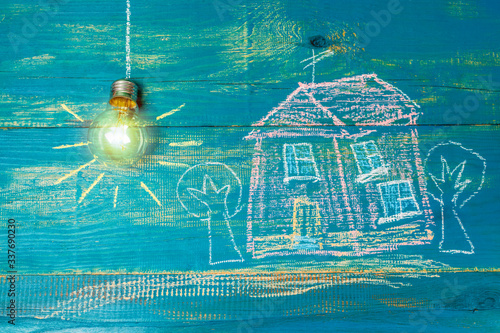 Obraz na płótnie energy saving light bulb and house drawn on wooden boards. Drawing with chalk. w salonie