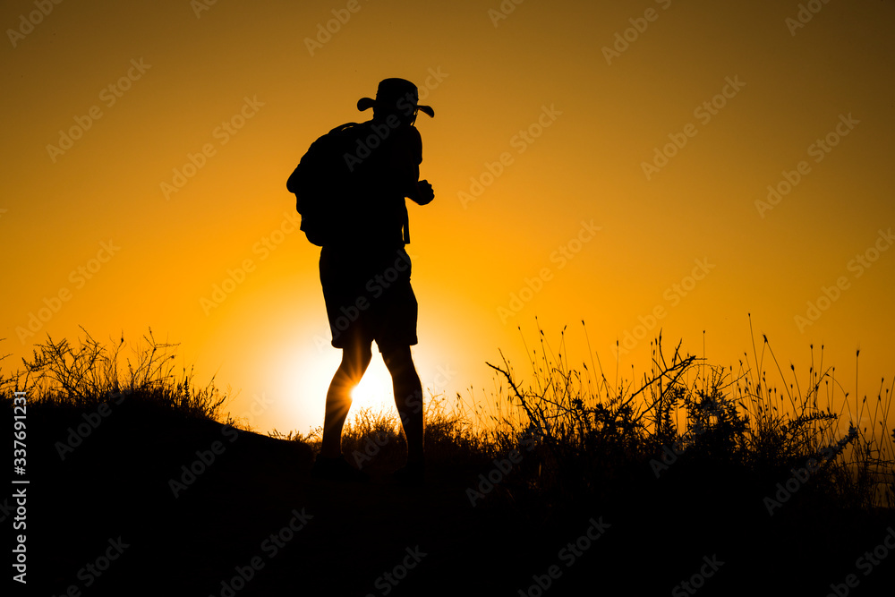 Silhouette of a womanwith a backpack in thesunset.