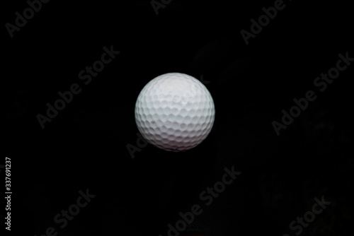 A white golf ball isolated against a black background.