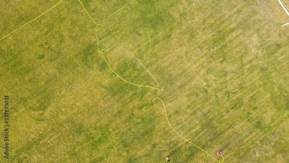 Top down aerial view of football field surface covered with green grass and sprinklers spraying water. Top down aerial view of football field surface covered with green grass and sprinklers spraying water.