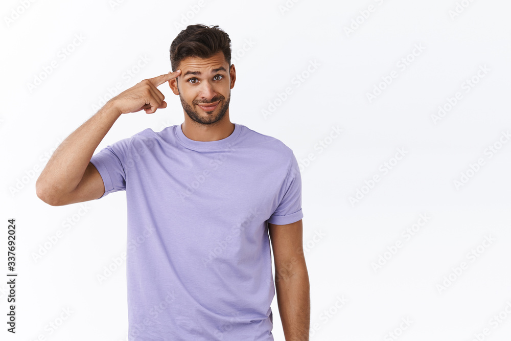 Someone is crazy. Displeased young bearded guy rolling index finger over temple and gaze with disbelief or disdain, smirk awkward react on person acting stupid or insane, stand white background Someone is crazy. Displeased young bearded guy rolling index finger over temple and gaze with disbelief or disdain, smirk awkward react on person acting stupid or insane, stand white background