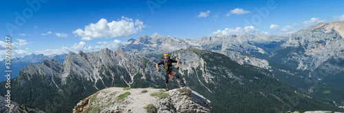 A tourist stands and poses against the backdrop of a mountain panorama in the Dolomites