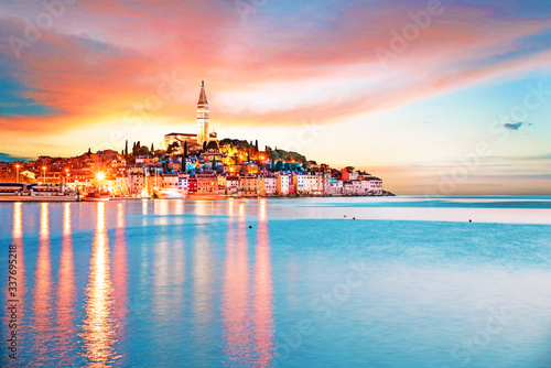 Obraz na płótnie Beautiful magical city landscape with sea, colorful houses and an ancient tower in Rovinj, Croatia at evening lights at sunset. popular tourist attraction. (vacation, rest - concept) w salonie
