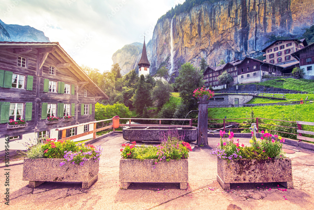 The picturesque landscape with flowers, a waterfall and canyon church in Lauterbrunnen in the Swiss Alps, Switzerland, Europe