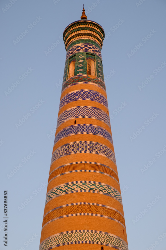 Minaret Islam Khoja in Khiva, Uzbekistan. Old minaret on the sky background in sunset. Central Asia travel view.