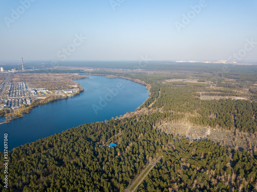 A lake between the city and coniferous forest on the outskirts of Kiev. Aerial drone view.