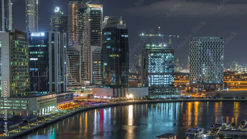 Night city with bright scyscrapers and luxury small houses aerial timelapse near canal in Business Bay, Dubai, United Arab Emirates Night city with bright scyscrapers and luxury small houses aerial timelapse near canal in Business Bay, Dubai, United Arab Emirates