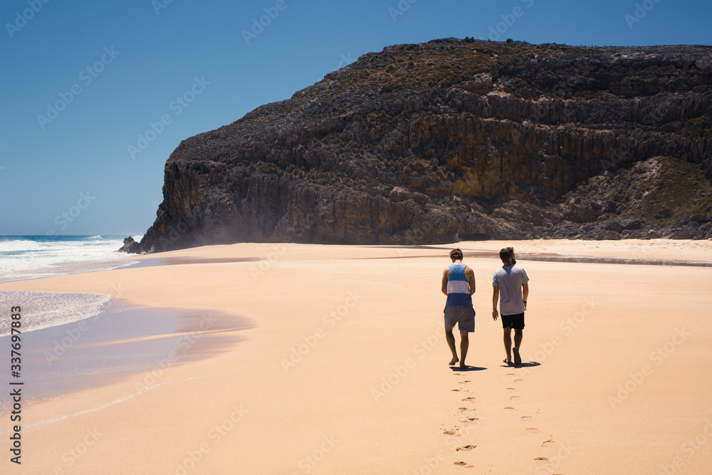 Two guys walking on an empty beach