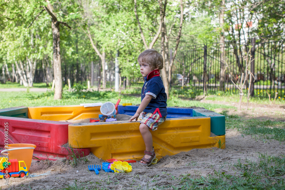 Kid in the sandbox play with sand and baby cookie cutters in sunny day in summer. Kid in the sandbox play with sand and baby cookie cutters in sunny day in summer.