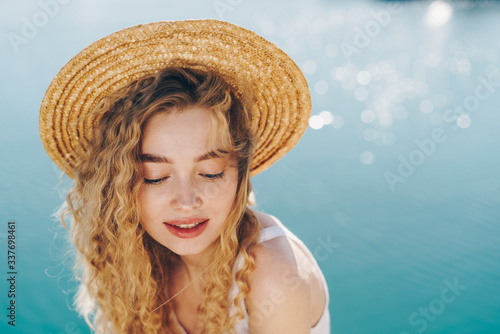 Portrait of a beautiful girl in a hat on a background of blue water