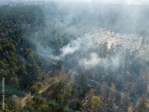 Fire in a forest cemetery. Smoke envelops conifers. Aerial drone view.