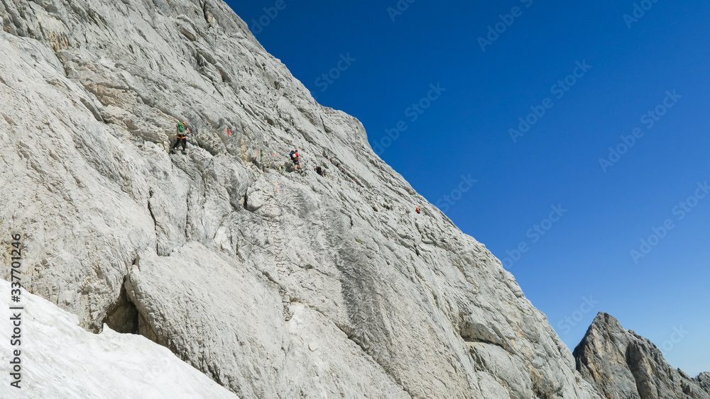 View of the glacier in the alps and tourists marching on it View of the glacier in the alps and tourists marching on it