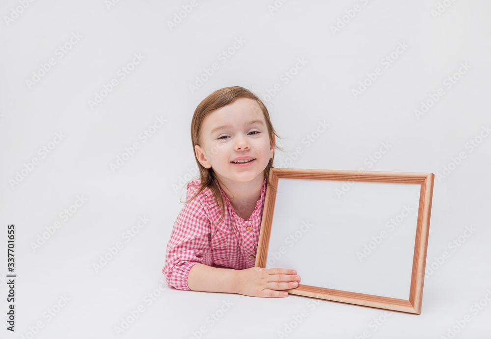 On white background with copy space.The girl is lying on her stomach on a white background and holding a frame with a white sheet. Cute girl in a plaid shirt. On white background with copy space.The girl is lying on her stomach on a white background and holding a frame with a white sheet. Cute girl in a plaid shirt.