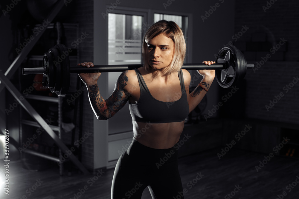 Athletic young blonde woman doing heavy barbell exercise in fitness class. Athletic young blonde woman doing heavy barbell exercise in fitness class.