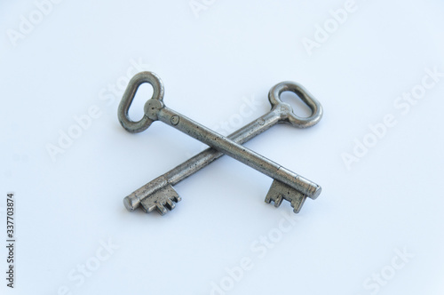 Two crossed retro keys isolated on white background. Metal, silver coloured, rusty door keys crossed © Anton Novak