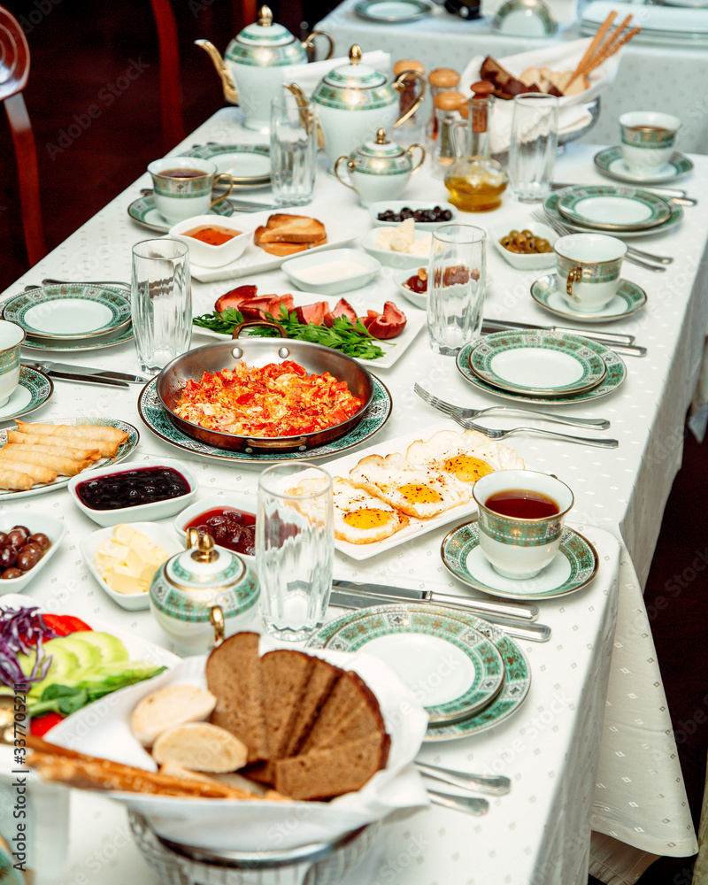 breakfast table with egg dish scrambled eggs breads sausages cheese and jams