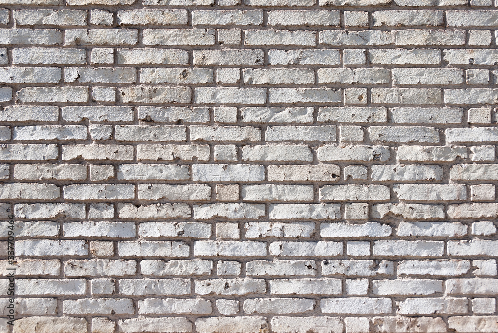 Full frame textured background of weathered brick wall with chipped and peeling white paint