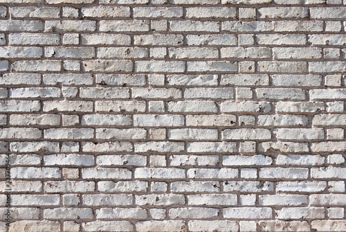 Full frame textured background of weathered brick wall with chipped and peeling white paint