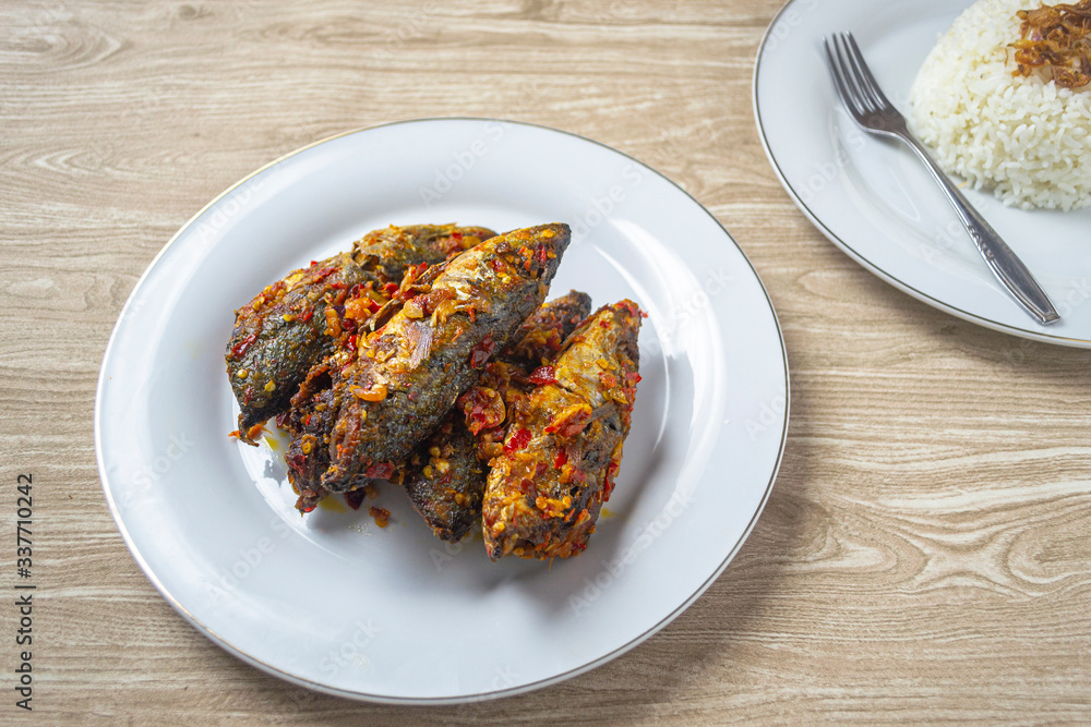 ikan balado in white plate. indonesian food made from fried fish cooked with red chili. has a savory and spicy taste and has good nutritional content for the body