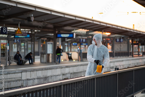 Ein Mann in einem Schutzanzug desinfiziert an einem Bahnhof ein Geländer, Kampf gegen die Ausbreitung des Coronavirus 