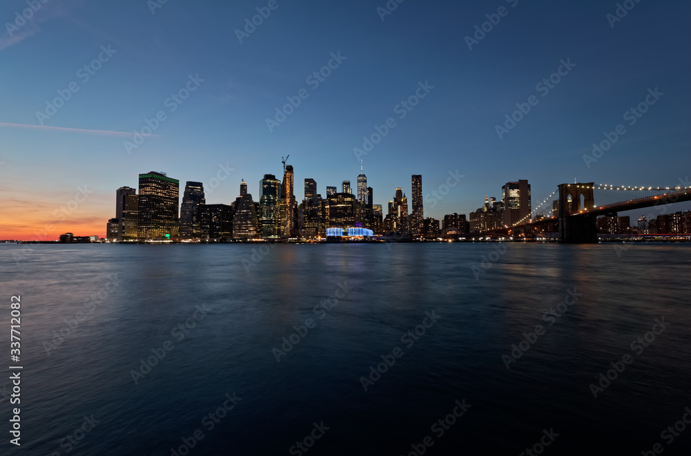 Long exposure wide panorama of Manhattan downtown at sunset from the Brooklyn Bridge Park.