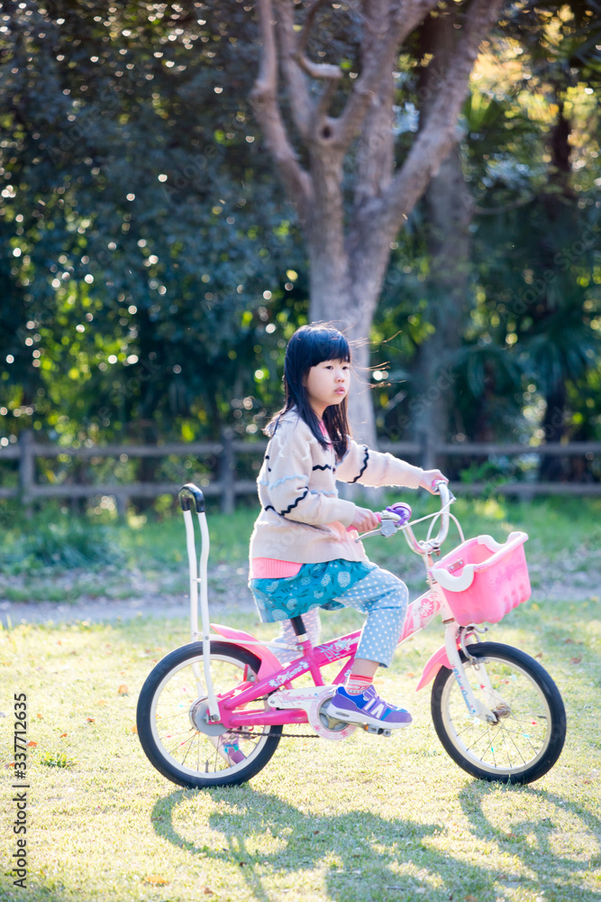 Obraz premium 春の公園で自転車を乗って遊んでいる可愛い子供