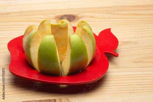 an Apple partially cut with an Apple cutter on a wooden background