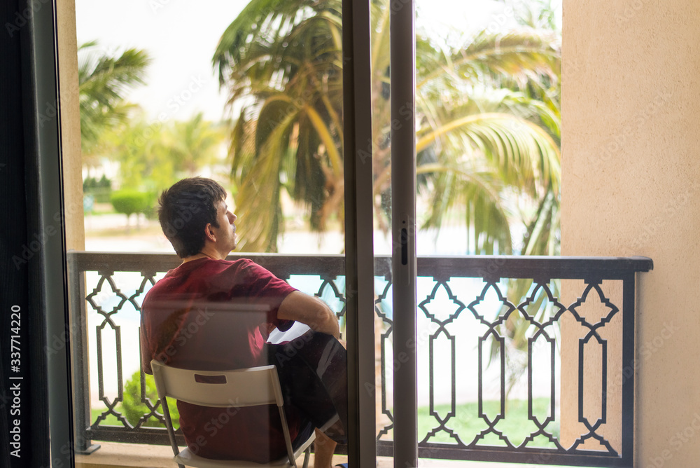 Man playing guitar on the balcony while spending time at home Man playing guitar on the balcony while spending time at home