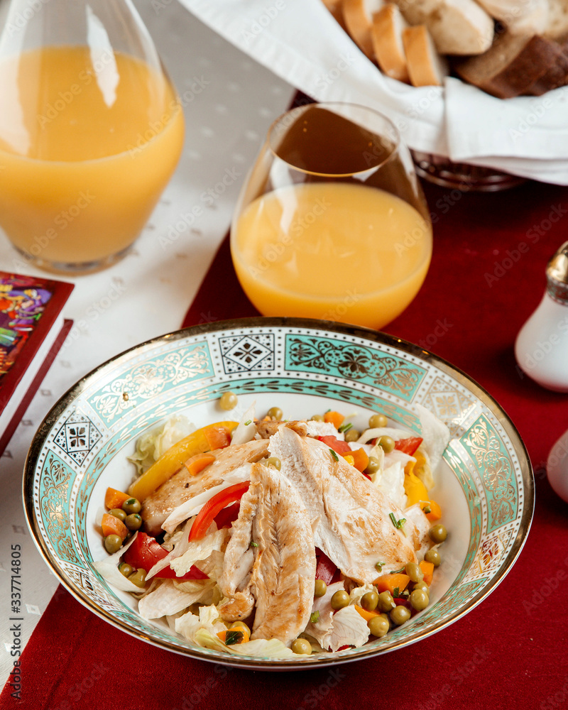 chicken salad with peppers peas and a glass of orange juice chicken salad with peppers peas and a glass of orange juice