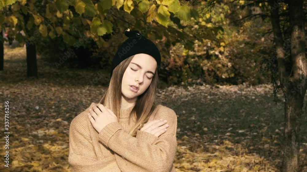 Portrait of young girl hugging herself at camera in autumn park