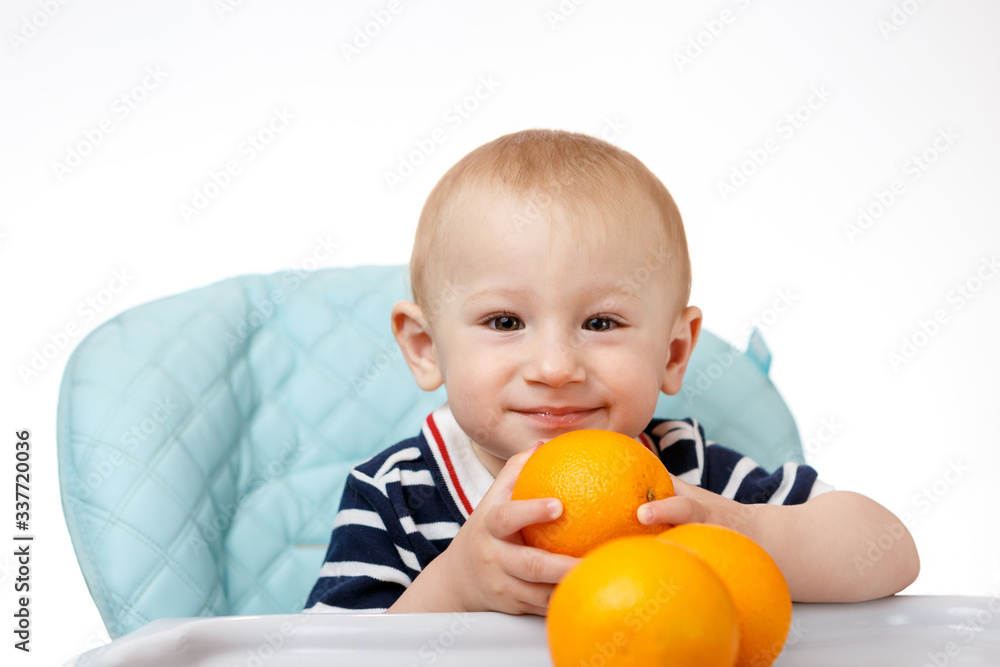 Cheerful little boy is eating oranges on a white background Cheerful little boy is eating oranges on a white background