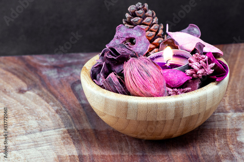 pourple tealight and dry potpourri in a wooden bowl photo