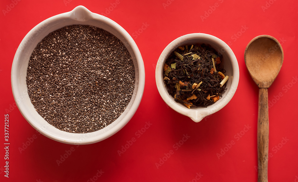 chia seeds and fruit tea in white bowls and a wooden spoon on a red background top view chia seeds and fruit tea in white bowls and a wooden spoon on a red background top view