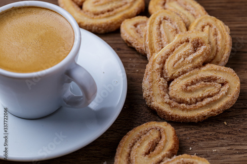 Xícara de café com biscoitos espalhado sobre mesa de madeira photo