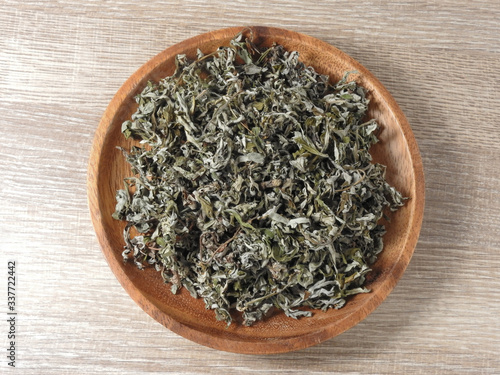 Top view of dry mugwort on wooden plate. Chinese medicine. During the Dragon Boat Festival, is usually hung on the door, which is used to ward off evil spirits and to drive away mosquitoes.